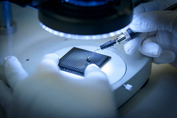 electronics worker checking small electronic chips in clean room laboratory close up